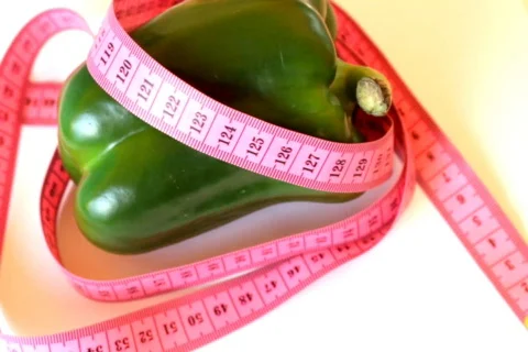 Tape measure wrapped around rotating green pepper Stock Footage