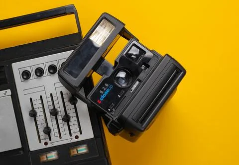 Tape recorder with equalizer, instant camera on a yellow background Stock Photos