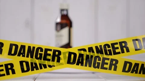 A tape with the word DANGER on the background of a blurred bottle of alcohol. Stock Footage 328024649