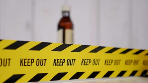 A tape with the word KEEP OUT on the background of a blurred bottle of alcohol. Stock Footage 329913595