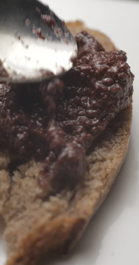 Tapenade olive puree on bread slow motion, vertical view Stock Footage 280523195
