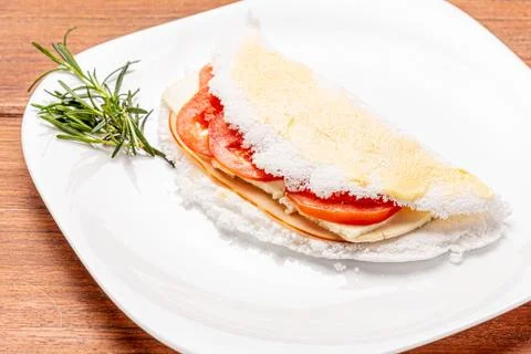 Tapioca filled with ham, cheese and tomato, on wooden background. Stock Photos