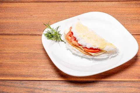Tapioca filled with ham, cheese and tomato, on wooden background. Stock Photos