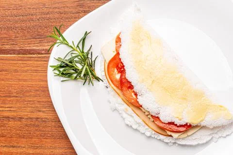 Tapioca filled with ham, cheese and tomato, on wooden background. Stock Photos