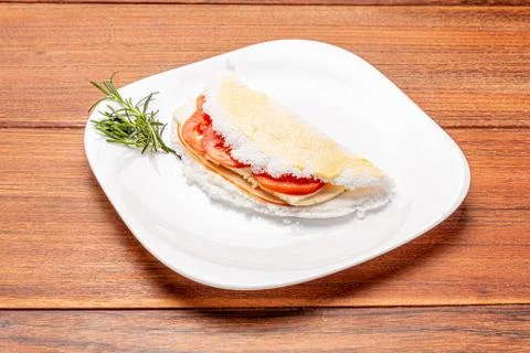 Tapioca filled with ham, cheese and tomato, on wooden background. Stock Photos