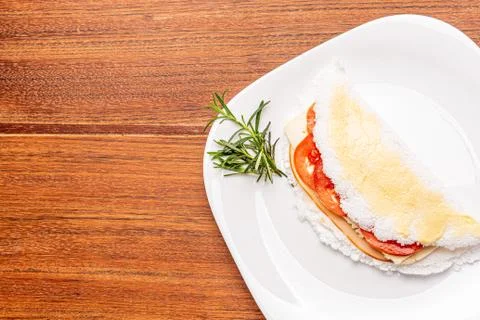 Tapioca filled with ham, cheese and tomato, on wooden background. Stock Photos