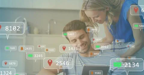 Tapping couple on sofa using tablet in open plan living room with floating Stock Photos