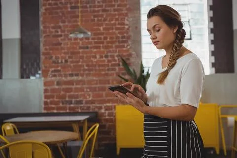 Tapping female server using tablet computer in modern café interior space, copy Foto stock