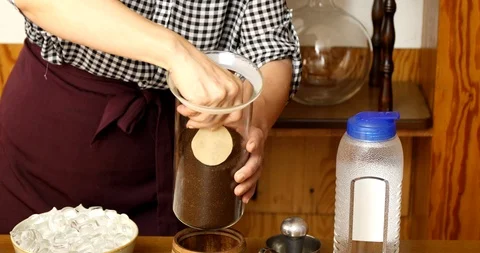 Tapping on glass container with ground coffee to make it flat and putting paper Stock Footage 111302873