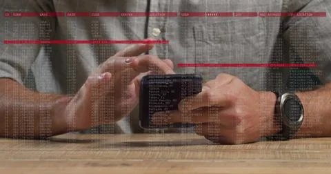 Tapping man in gray shirt using smartphone at tabletop with stylus, watch, code 写真素材