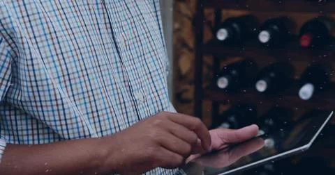 Tapping mid adult man using tablet at wine shop, with checked-shirt, wooden wine Stock Photos