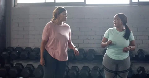 By tapping smartwatch, warming up, Diverse female workout partners entering gym Stock Footage 344534960