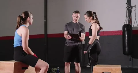 Tapping tablet and scrolling details, male coach guiding female trainees in Stock Footage 340454179