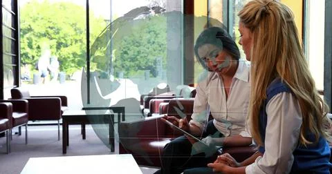 Tapping tablet, button-down woman leaning, showing content to co-worker near Stock Photos