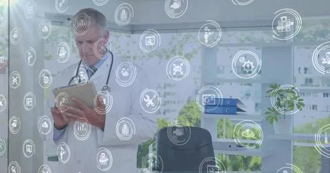 Tapping tablet computer, doctor in lab coat with stethoscope interacting in Stock Photos