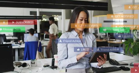 Tapping tablet, Korean woman in patterned blouse and pants at open office, with Stockfoto's