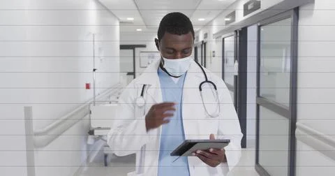 Tapping tablet, physician in lab coat, scrubs, mask and stethoscope reviewing Stock Photos