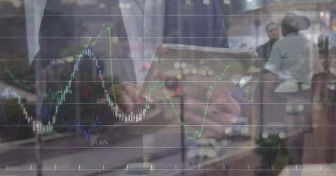 Tapping tablet, suited man navigating financial charts in office lobby, with Stock Photos