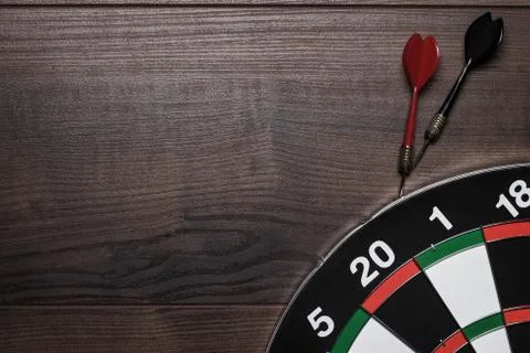 Target and two darts over brown wooden table background Stock Photos
