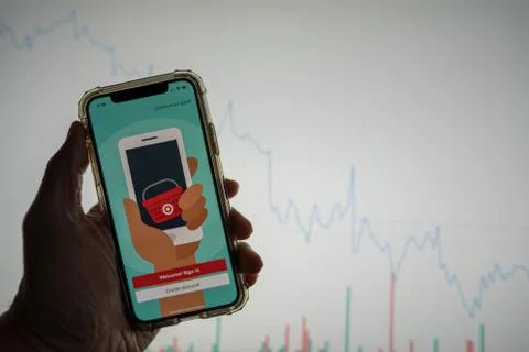 Target mobile app login on iPhone in front of white stock market chart with Stock Photos