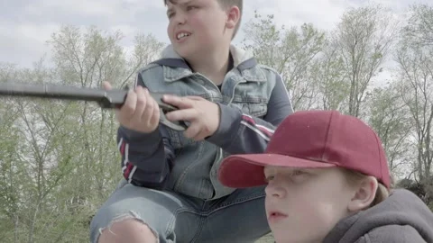 Target practice as a boy shoots a bb gun as his friend watches. Video stock 169733299