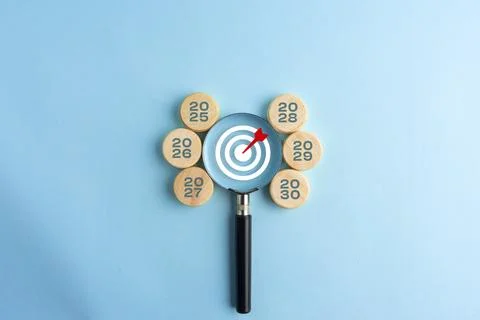 A target with a red arrow viewed through a magnifying glass, surrounded by .. Stock Photos