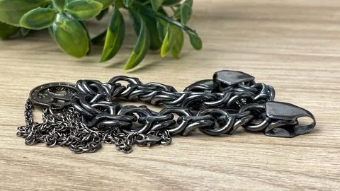 Tarnished silver chains on a wooden surface Stock Photos