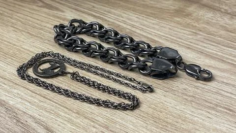 Tarnished silver chains on a wooden table Stock Photos