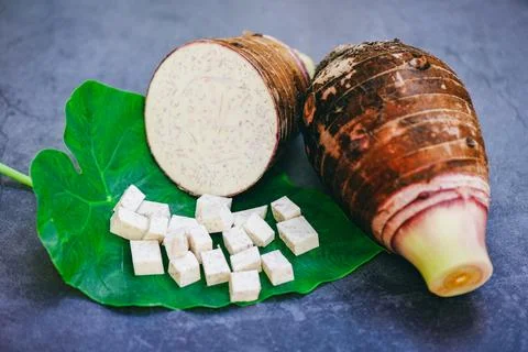 Taro root with half and slice cubes on taro leaf and wooden background, Fre.. Stock Photos