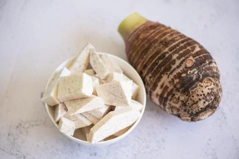Taro root with slice cubes on bowl and table background, Fresh raw organic .. Stock Photos