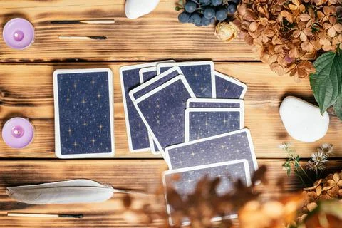Tarot cards spread face down on wooden surface with candles, stones, autumn p Foto stock
