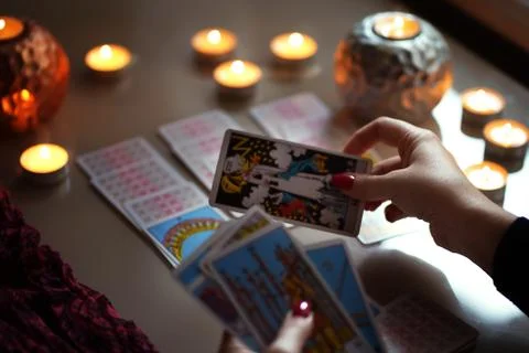 Tarot reader picking tarot cards near burning candles. 스톡 사진