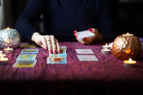 Tarot reader picking tarot cards near burning candles. Stock Photos