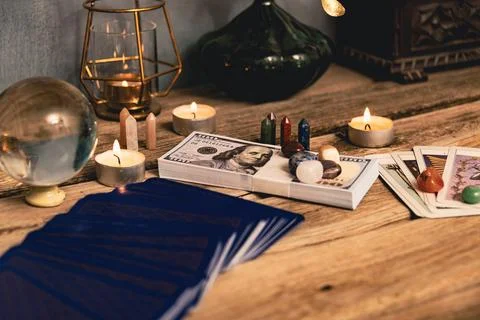 A tarot spread with The Fool card, hundred-dollar bills, and various crysta.. Stock Photos