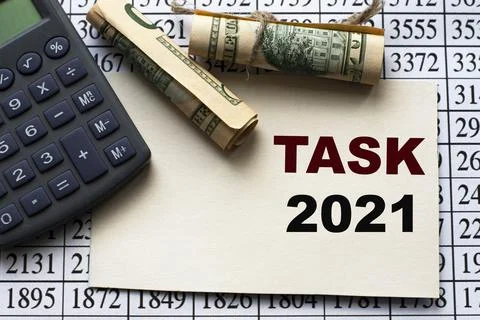 TASK 2021 word on a white sheet against a table with numbers, banknotes and c Stock Photos