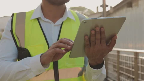 Taskmaster in vest inputs data in tablet computer checking construction site Stock Footage 305761647