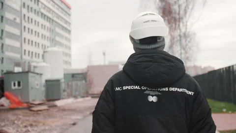 Taskmaster walks to inspect work along construction site Stock Footage 198757442