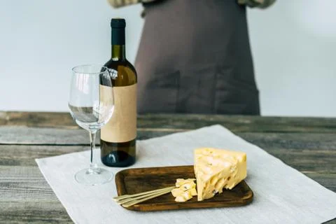 Taster standing at table with Bottle of white wine, empty glass and cheese Stock Photos