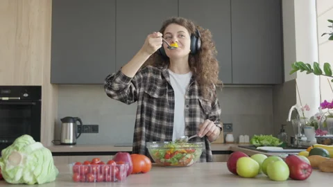 Tasting Fresh Salad While Listening To Music In Modern Cozy Kitchen 動画素材 311282839