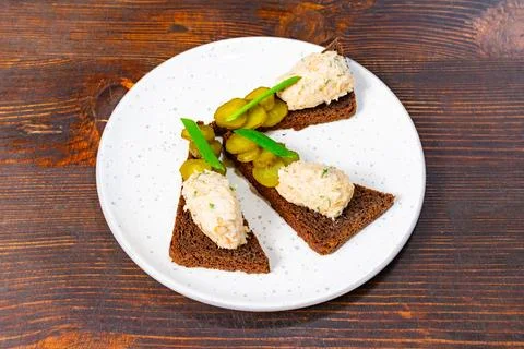 Tasty appetizers featuring brown bread, fish spread, and pickles Stock Photos