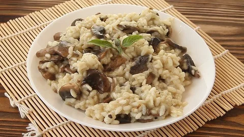 Tasty appetizing risotto on  white plate on  wooden table Stock Footage 129346007
