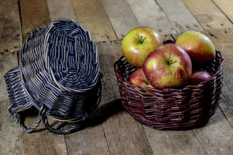 Tasty apples in basket on kitchen table. Autumn season. Wooden table. Stock Photos