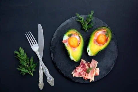 Tasty baked avocado with an egg on a black background Stock Photos