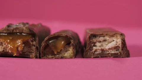 Tasty bitten chocolate candy bars slider move on pink background isolate Stock Footage 135551356
