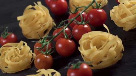 Tasty branch red cherry tomatoes single yellow Tagliatelle pasta rotating black Video stock 148165576