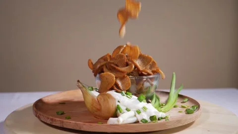 Tasty bread crackers falling on a wooden plate with onion in slow motion Stock Footage 124377814