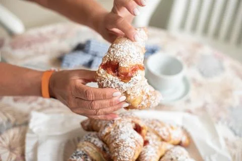 Tasty brioche filled with jam, split by feminine hands Stock Photos