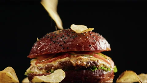 Tasty burger and falling chips close-up, cooked juicy sandwich, fast food Stock Footage 170329409