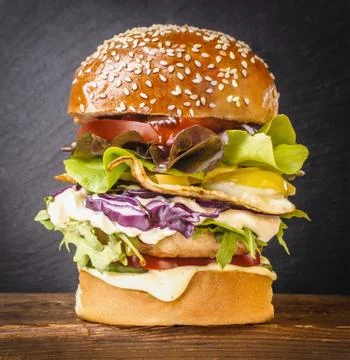 Tasty burger with fried egg on table against black background, closeup Stock Photos