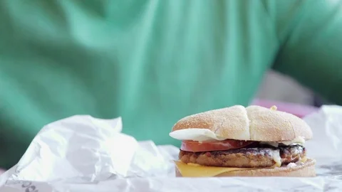 Tasty burger is great on a table. A man takes his hands and eats, try the taste Stock Footage 74428088